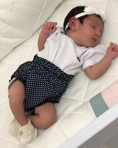 a baby laying on top of a white bed