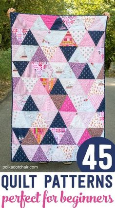 a pink and blue quilt hanging on the side of a road with trees in the background