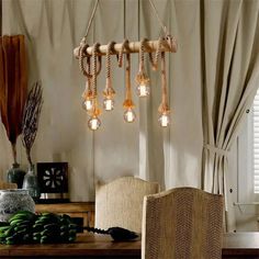 a dining room table with chairs and lights hanging from the ceiling