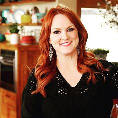 a woman with red hair is smiling at the camera and wearing earrings on her ear