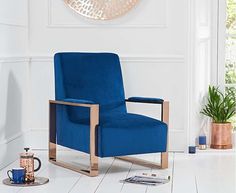 a blue chair sitting on top of a white floor next to a potted plant