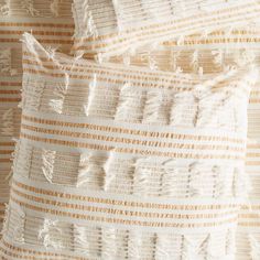 closeup of an orange and white striped pillow with fringes on the back side