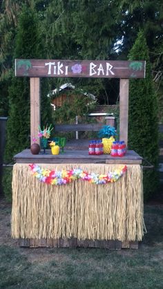 a tiki bar set up in the middle of a yard with grass and flowers