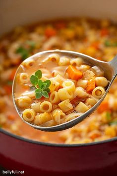 a ladle full of macaroni and cheese soup being held by a spoon