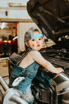 a young child sitting on the hood of a car with his headband wrapped around