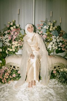 a woman sitting on top of a white couch next to flowers and candles in the background