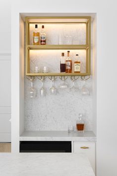 the shelves are filled with liquor bottles and glasses on top of marble countertops in this kitchen