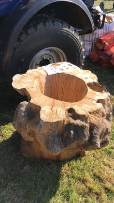 a wooden stump sitting in the grass next to a truck