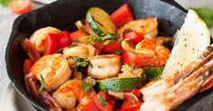 a skillet filled with shrimp and vegetables