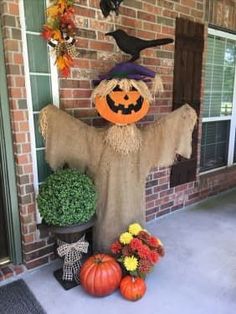 a scarecrow standing in front of a house decorated with pumpkins and other decorations