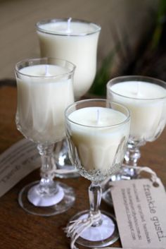 three glasses filled with white candles on top of a table