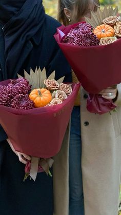 two people holding bouquets with flowers and pumpkins on them, in the fall