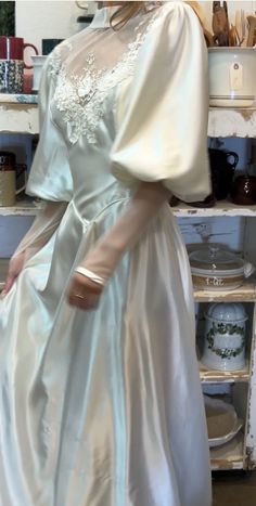 a woman in a white dress standing next to a shelf