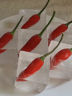 four pieces of ice with red peppers on them sitting on a white plate next to each other