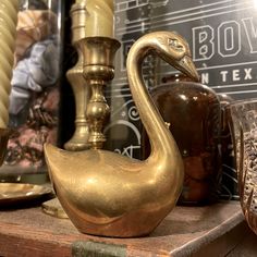 a brass swan figurine sitting on top of a wooden table next to candles