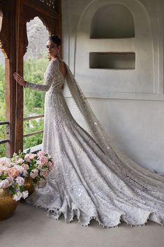 a woman in a wedding dress leaning against a wall with her hand on the shoulder