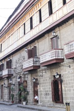 an old building with two people sitting on the balcony