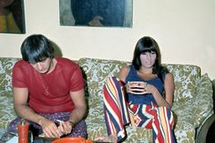 two people sitting on a couch looking at their cell phones