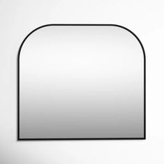 an oval mirror hanging on the wall with a black frame and white walls behind it