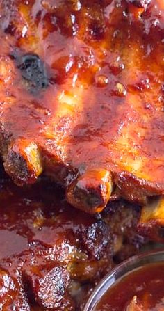 barbecue ribs covered in bbq sauce with a bowl of ketchup on the side