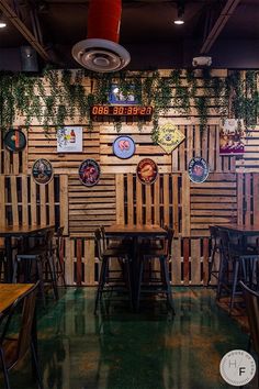 the interior of a restaurant with wooden tables and chairs, hanging plants on the wall