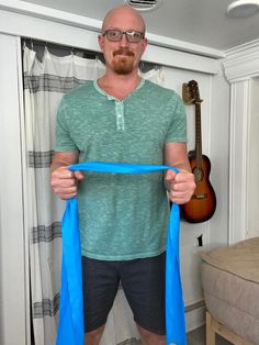 a man holding a blue ribbon in front of his face while standing next to a guitar