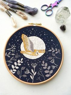 an embroidery project with scissors, thread and other crafting supplies on a table top