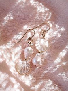 These asymmetrical carved Seashell and Baroque Pearl Earrings make beautiful simple statements. Seemingly plucked straight from the ocean, the luminous, organic white pearls sway and illuminate in the light. Wear these unique pearl, shell, and gold earrings for a modern upgrade.✦ DETAILS ✦✧ Name: Momi - (MOH mee) - pearl.✧ 14kt Gold Filled.✧ Genuine Freshwater Baroque Pearls.✧ Carved Mother of Pearl Seashells.✧ All Ke Aloha Jewelry pieces come packaged thoughtfully, beautifully, and ready for gi Shell Pearl Earrings, Graceful White Pearl Earrings For Gift, Unique Pearl Dangle Earrings, Graceful White Pearl Earrings With Pendant, Delicate White Pearl Pierced Earrings, Pearl Drop Shell As A Gift, Pearl Shell Jewelry For Weddings, Unique Dangle Pearl Earrings, Unique Pearl White Pearl Jewelry