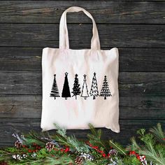 a tote bag sitting on top of a wooden table next to evergreen branches and pine cones