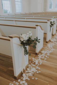 the aisle is decorated with white flowers and greenery