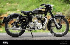 an old black motorcycle parked on the side of the road in front of some grass