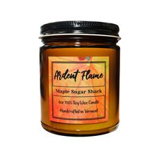 a jar of maple sugar with an orange label on the top and bottom, in front of a white background