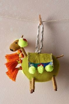 a small stuffed animal hanging from a clothes line on a string with two pom poms attached to it