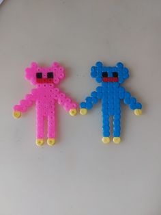 two plastic toys made to look like animals on a white surface, one is pink and the other is blue