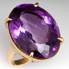 This superb vintage cocktail ring is accented with one (1) oval cut natural amethyst that weighs approximately 22.60cts that is set into a four-prong setting. The gallery features an openwork design. The ring measures 23.9mm at the top, rises 10.5mm above the finger, tapering to 2.6mm wide and 1.5mm thick at the base of the shank. It is currently a size 6.25. Antique Cocktail Ring, Amethyst Rings, Amethyst Cocktail Ring, Amethyst Ring Vintage, Amethyst Set, Vintage Cocktail Ring, Vintage Cameo, Violet Purple, Amethyst Jewelry