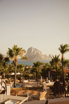 an outdoor dining area with palm trees and mountains in the background