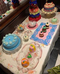 a table topped with lots of cakes and cupcakes