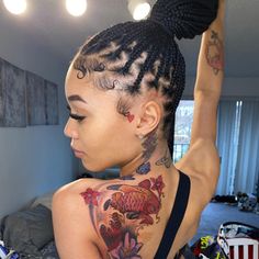 a woman with fish tattoos on her back and neck is standing in front of a bed