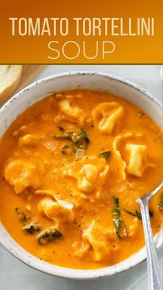 tomato tortellini soup in a white bowl with a spoon and bread on the side