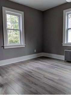 an empty room with two windows and a radiator