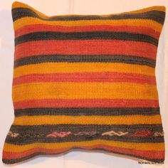 an orange and black striped pillow sitting on top of a white wall