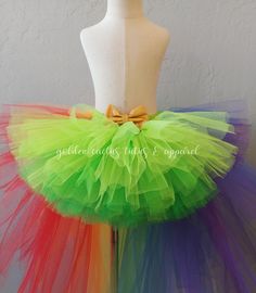 This high low tutu is next level. The front is an Ombre green and topped with a shiny gold bow. The back is over 100 yards of tulle with tiered layers creating a wild rainbow look. The back layers have glitter tulle mixed in. Sizing Info: 1-3T is roughly 6" long in the front, 20" long in the back 4-5T is roughly 8 inches long in the front, 25" long in the back 6-8 years is roughly 10 long in the front, 30" long in the back Whimsical Green Tutu Dress For Dress-up, Gold Tulle Tutu Dress With Ruffles, Green Spring Tutu Dress For Birthday, Carnival Tulle Tutu Dress, Green Spring Birthday Tutu Dress, Spring Green Tutu Dress For Birthday, Playful Rainbow Tulle Tutu Dress, Whimsical Rainbow Tulle Tutu Dress, Whimsical Multicolor Tulle Tutu Dress