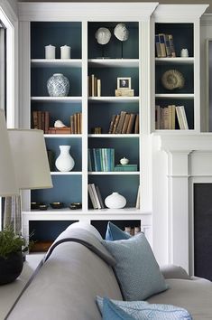 a living room filled with lots of furniture and bookshelves next to a fire place