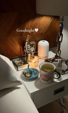 a bed with a night stand, lamp and food on it