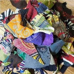 a pile of multicolored scarves sitting on top of a wooden floor