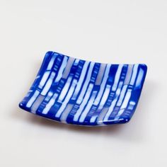 a blue and white striped dish sitting on top of a white tableclothed surface