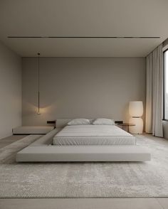 a large white bed sitting in the middle of a room next to a tall window