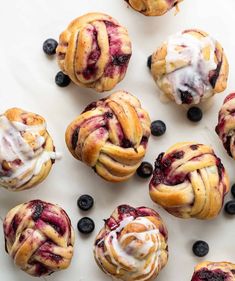 blueberry rolls with icing and blueberries scattered around them