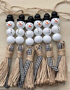 several snowmen with black hats and scarfs on top of each other next to some tassels