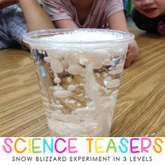 two children laying on the floor next to a plastic cup filled with ice and water